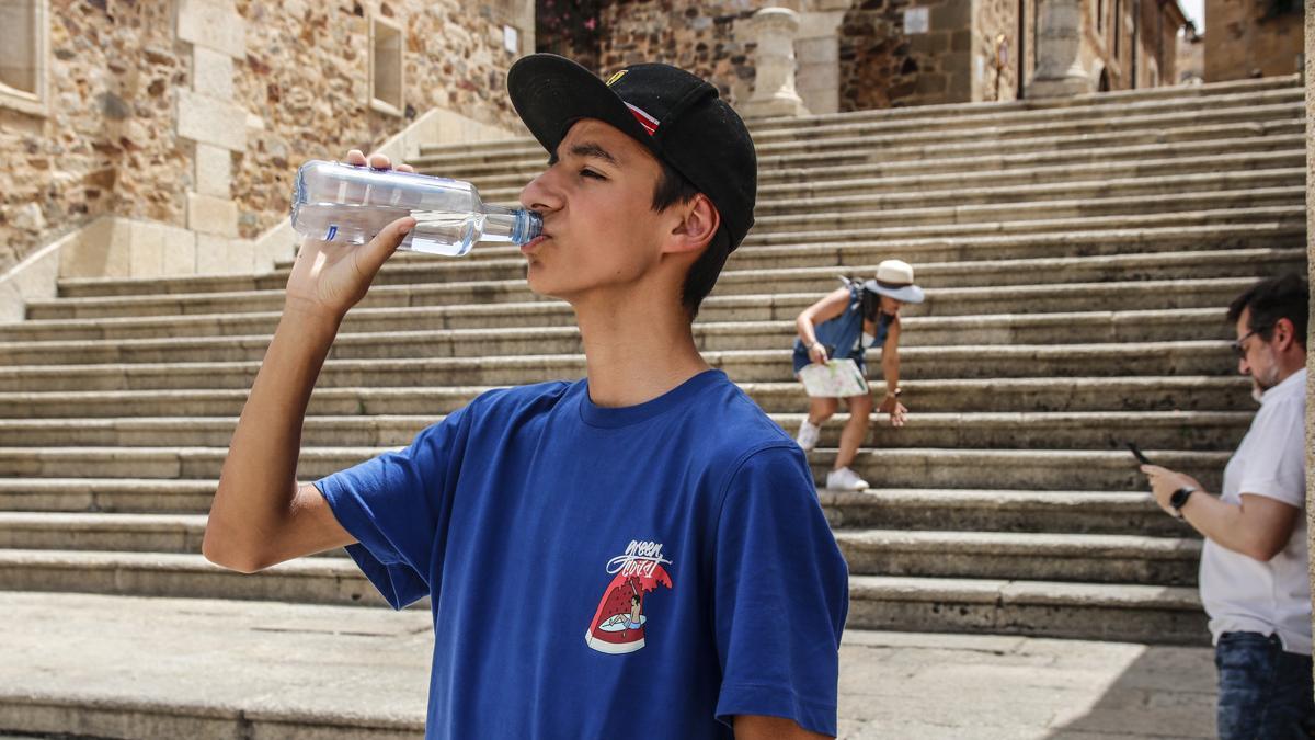 Un joven bebe agua en plena ola de calor en la plaza Mayor de Cáceres.