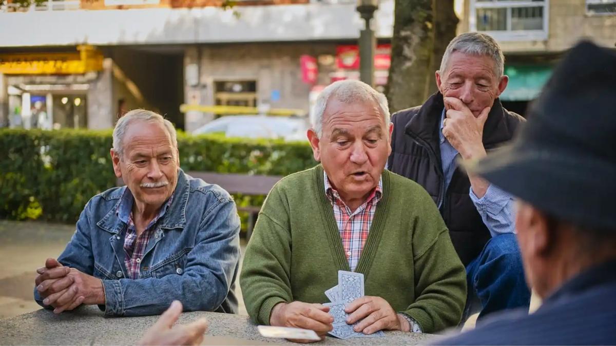 Un grupo de jubilados jugando a cartas en un parque.