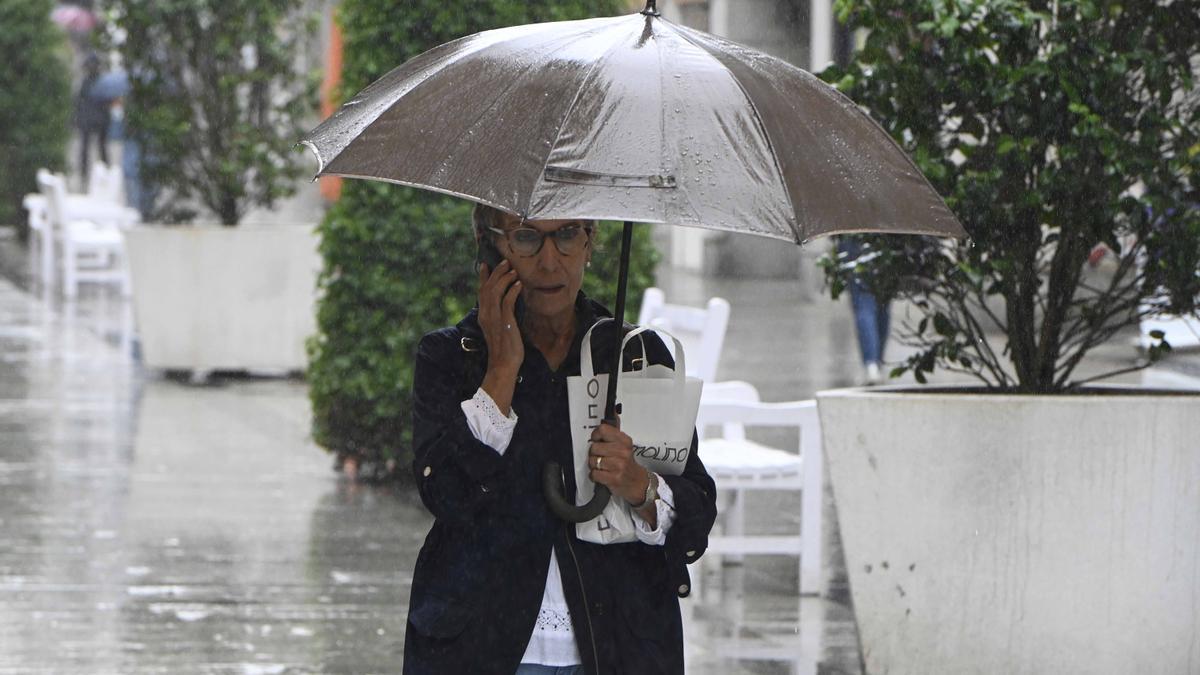 Una mujer camina bajo la lluvia por el centro de Vigo, esta mañana