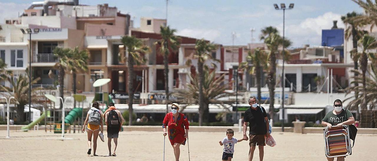 Bañistas con los restaurantes y arrocerías típicos del paseo de Neptuno al fondo.