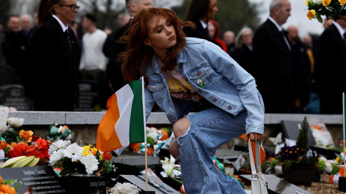 Una chica deposita flores en la tumba de Bobby Sands, exmiembro del IRA, durante la conmemoración del 25 aniversario de los Acuerdos de Paz en Irlanda del Norte.