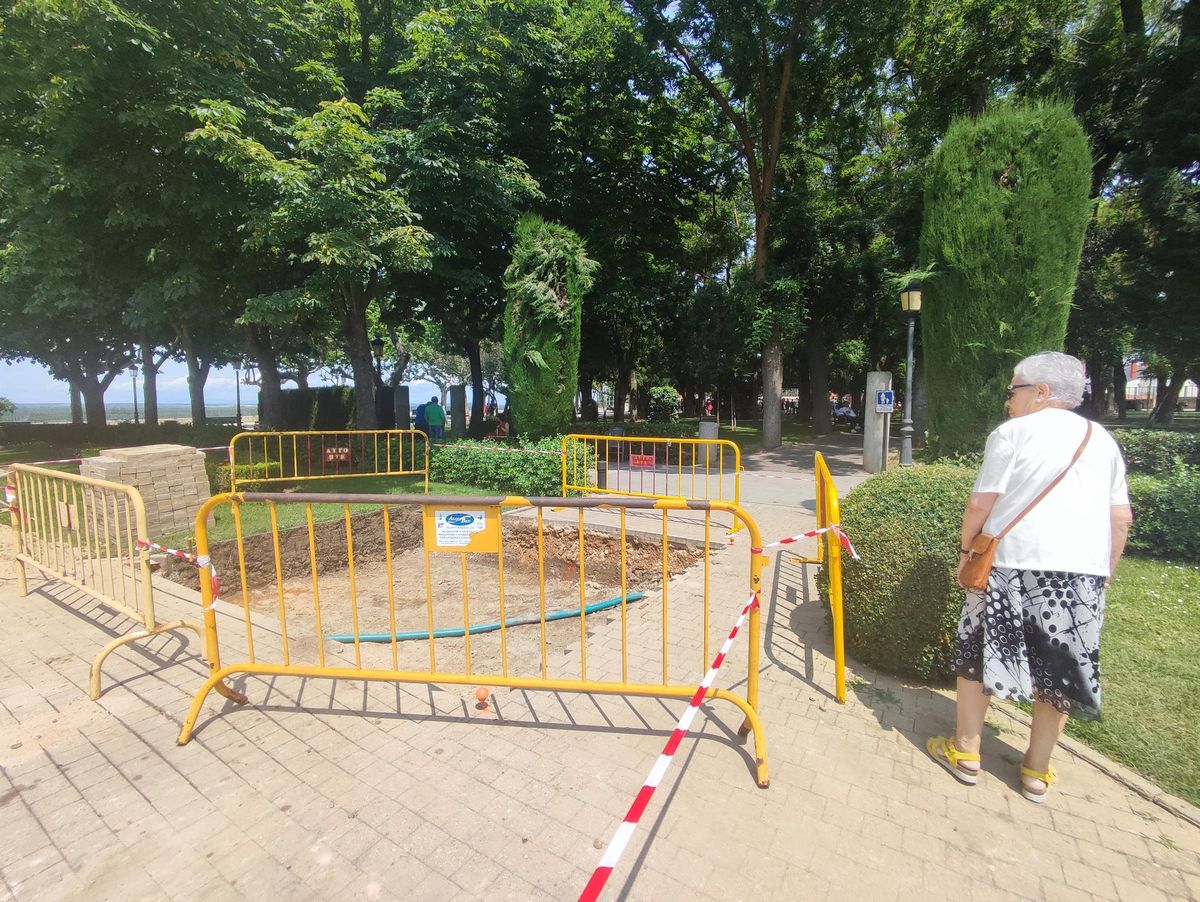 Una mujer observa al paso una de las catas realizadas en el jardín próximo al Parador.