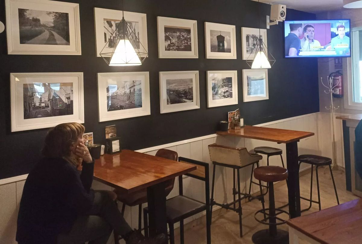 Una mujer observa la televisión en un bar de Huesa