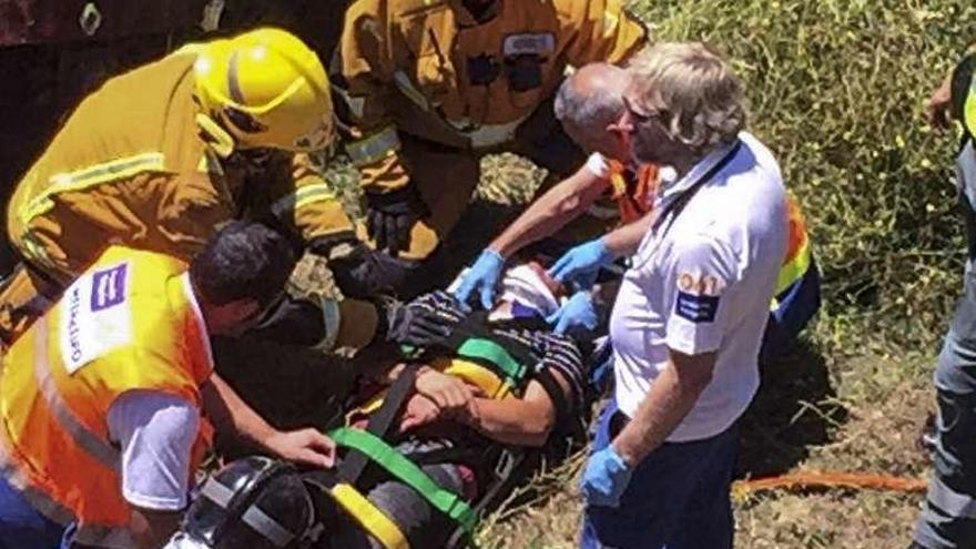 Bomberos y sanitarios asisten al herido antes del traslado. // FdV