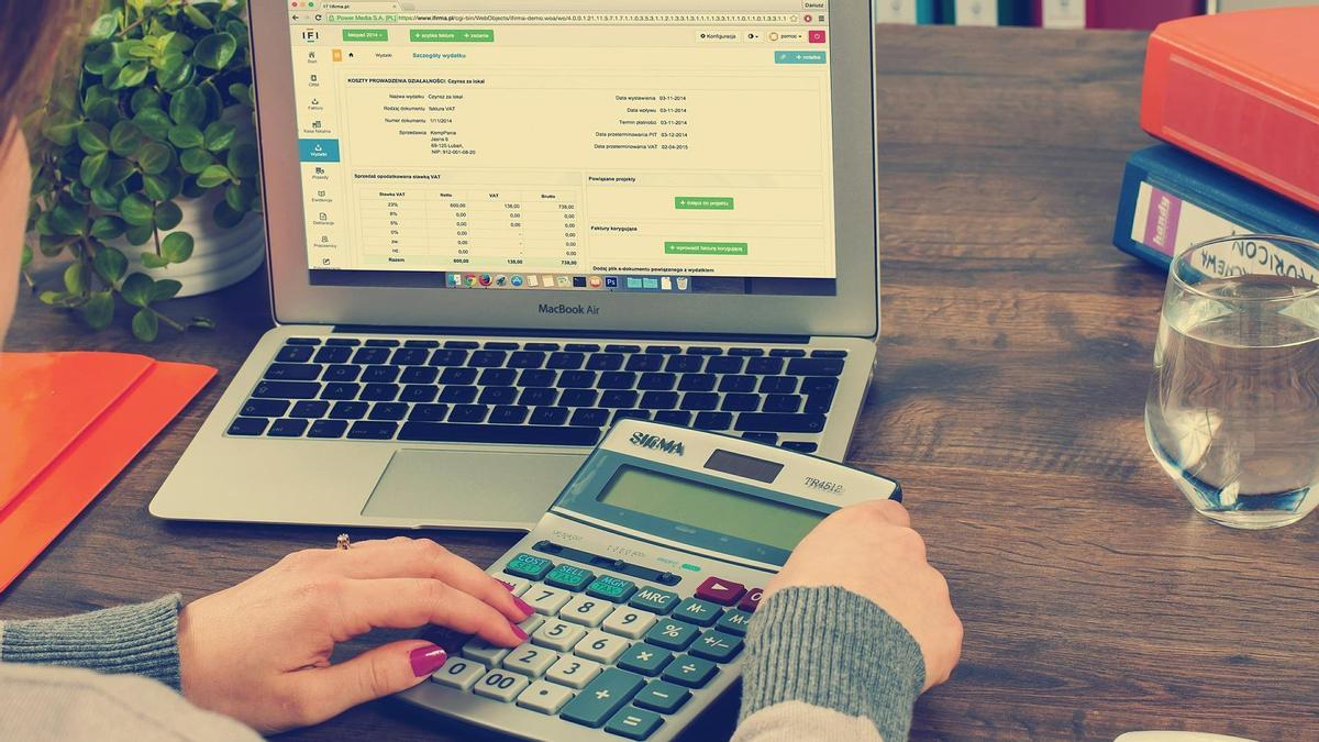 Una mujer realiza cuentas con una calculadora y un ordenador