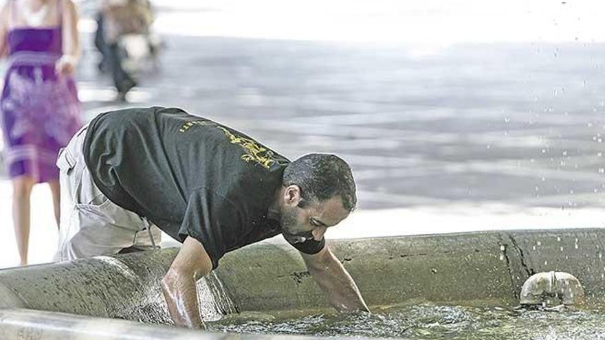 Un hombre refrescándose en una fuente.