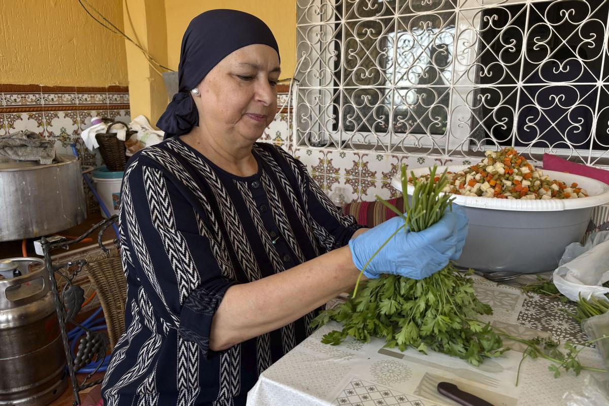 CEUTA, 11/08/2026.- En la puerta de la casa de Sabah, en Los Rosales, una de las barriadas de la periferia de Ceuta, los migrantes empiezan a llegar hasta dos horas antes de que se reparta la comida, apretándose pegados a la pared para resguardarse en la única franja de sombra que hay en toda la calle. Desde el primer día de la crisis migratoria, el hogar de Sabah dejó de ser una residencia privada para transformarse en un punto de socorro. En la imagen una voluntaria cocina en el domicilio de Sabah. EFE/Laura Rincón