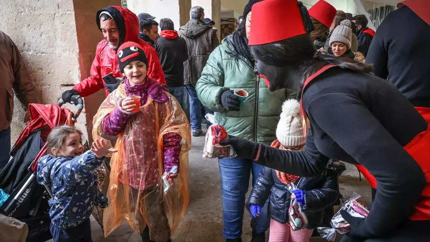 Los Pajes Reales atienden a los niños bajo los pórticos de la Plaça de Dins, por la lluvia