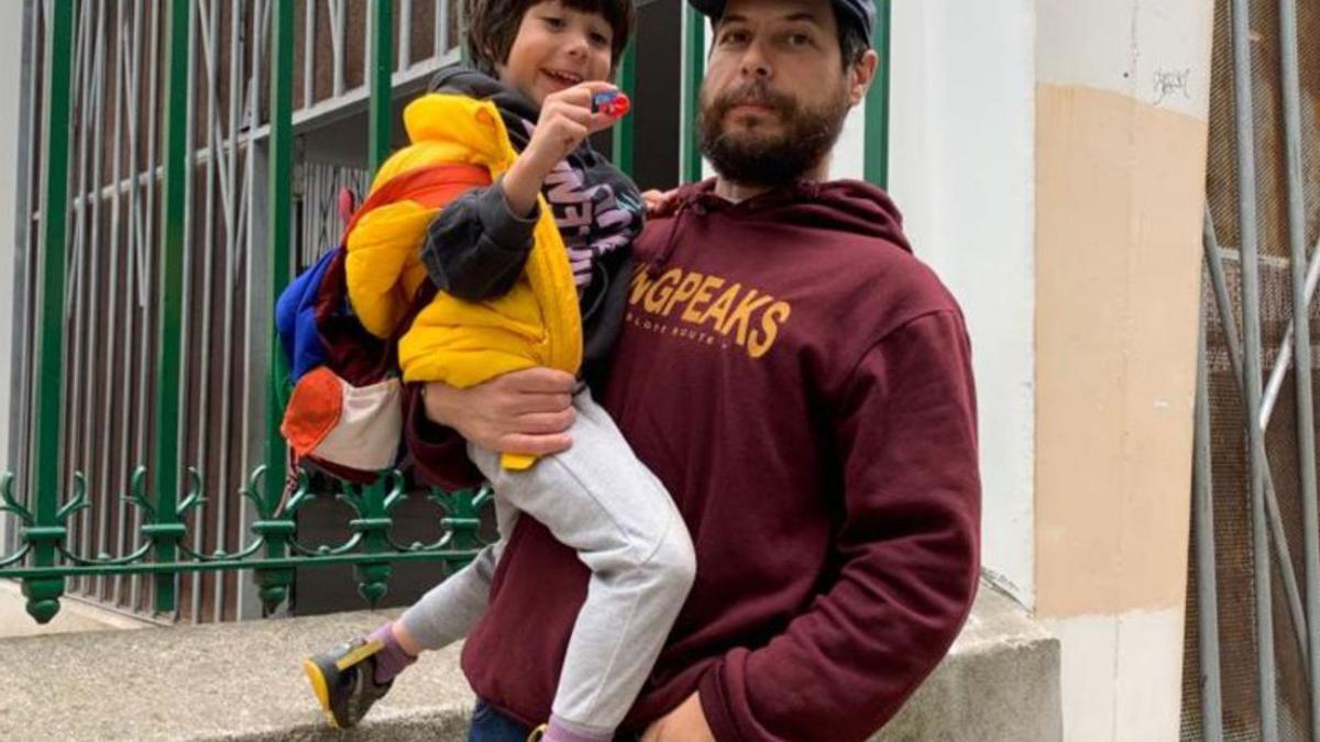 Rubén Quirós sostiene a su hijo Blas frente a las instalaciones del colegio Jovellanos de Gijón.