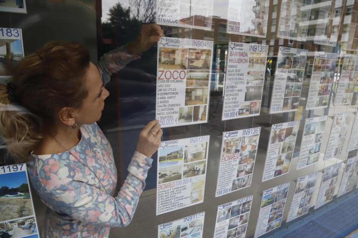 Una mujer recoloca anuncios de viviendas en una inmobiliaria.