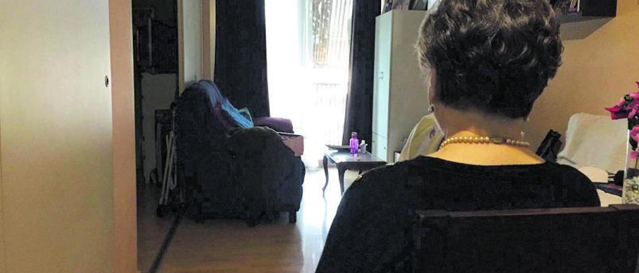 Una mujer jubilada que vive sola permanece sentada en una de las estancias de su vivienda en la ciudad de Alicante. | A.LOSA