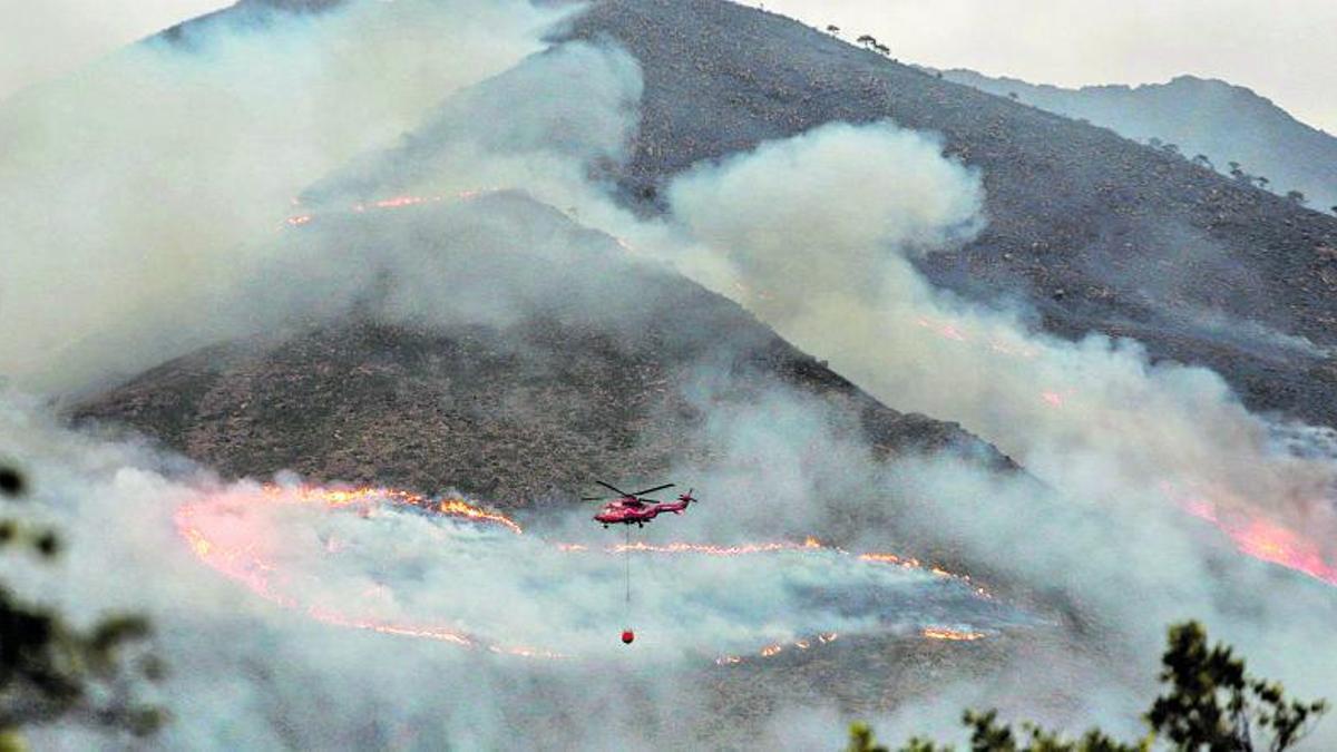 Un helicóptero arroja agua sobre las llamas que asolan Sierra Bermeja