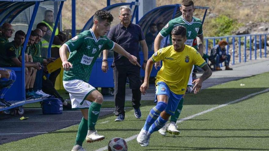 Pitu, del Coruxo, trata de eludir la entrada de un jugador del Las Palmas Atlético en el partido de ayer. // Pérez Curbelo/La Provincia