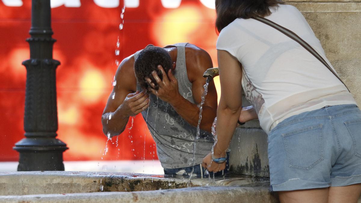 Dos personas se refrescan en una de las fuentes de Xàtiva.