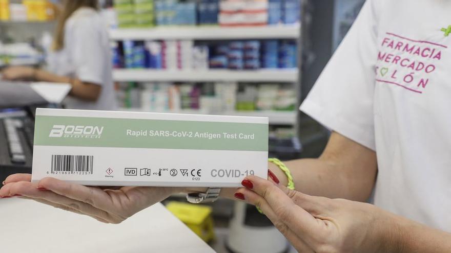 Una farmacéutica muestra una caja de test de antígenos.