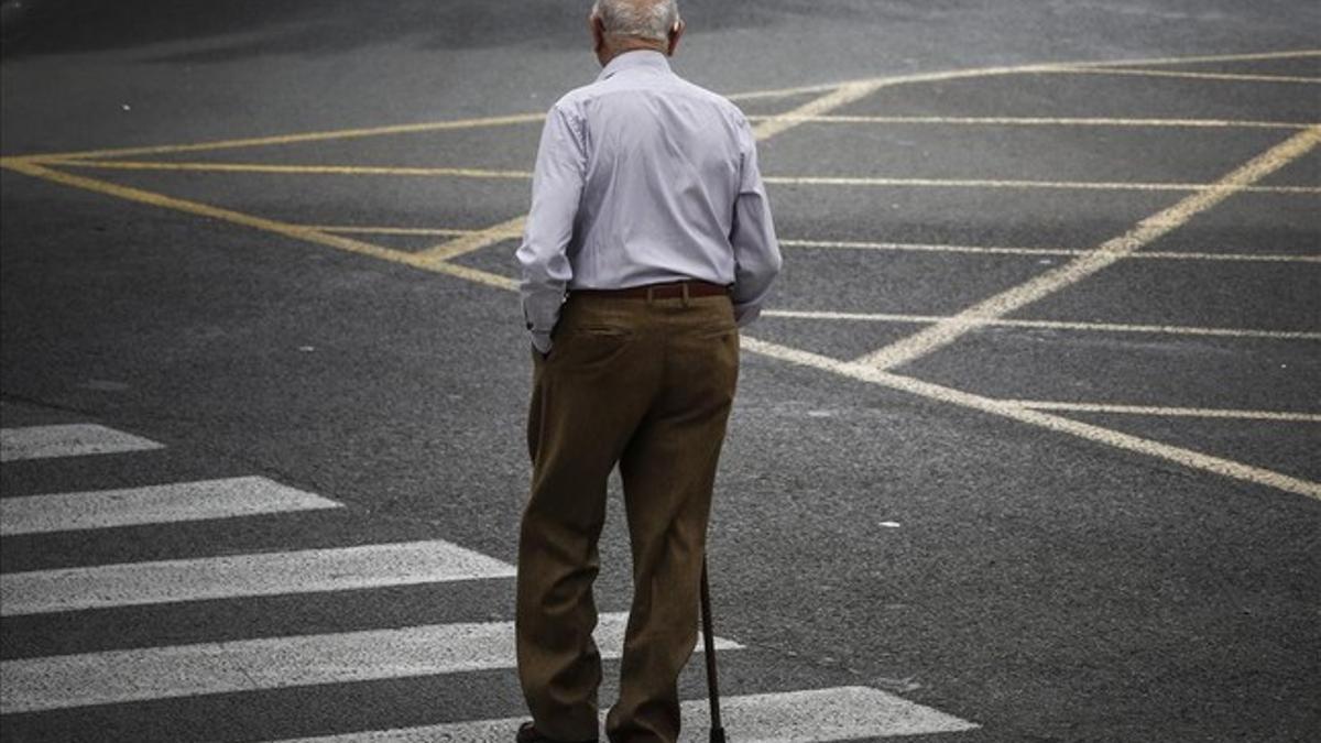 Un pensionista atraviesa una calle.