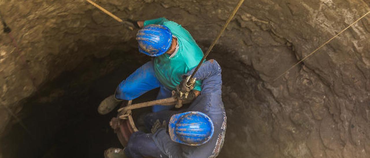 Dos trabajadores bajan al fondo del pozo de Tenoya, en Arucas.