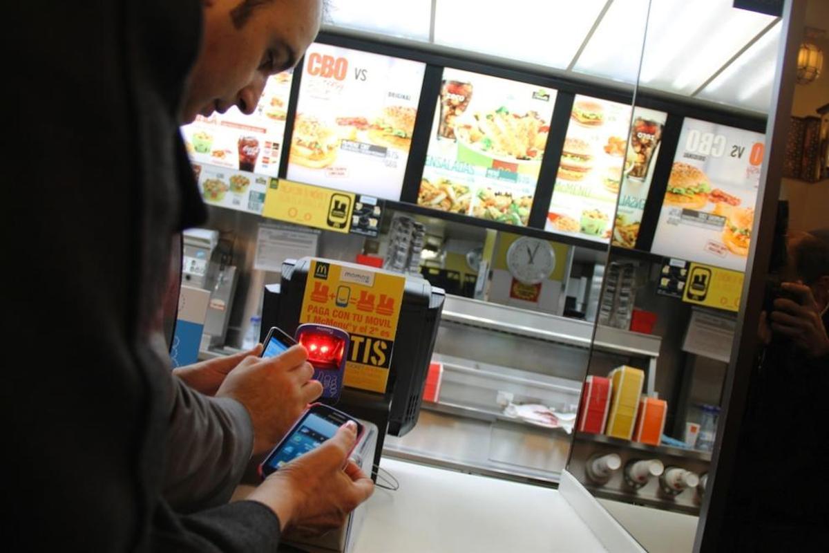 El concejal Mario Cortés paga con su móvil en un McDonald's de la capital.