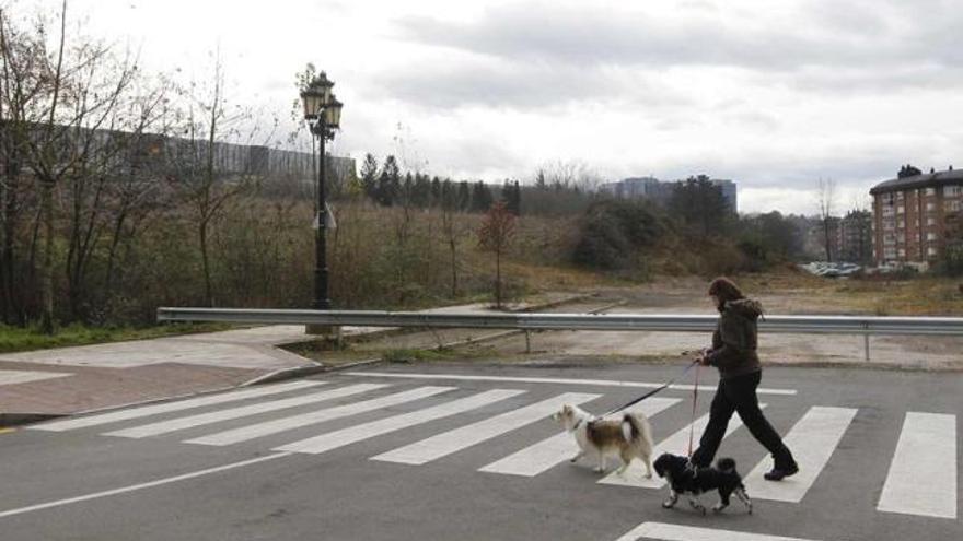 Una vecina pasa frente a la zona sin urbanizar del entorno del nuevo HUCA.