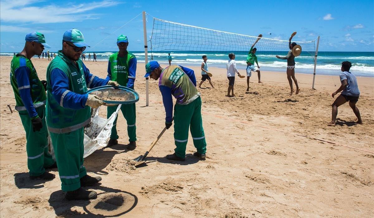 zentauroepp50714434 municipality workers clean oil as men play beach volley at a191105103610