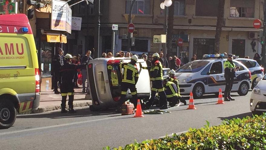 Los bomberos y el vehículo volcado en la Gran Vía Fernando el Católico.