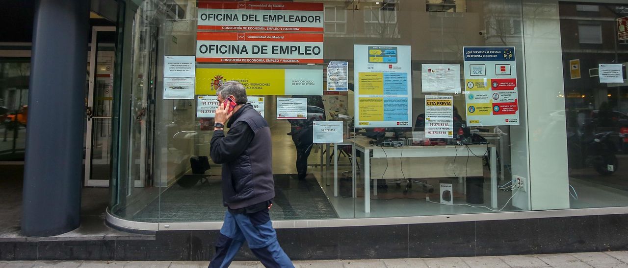 Un hombre habla por el móvil al pasar ante una oficina pública de empleo.