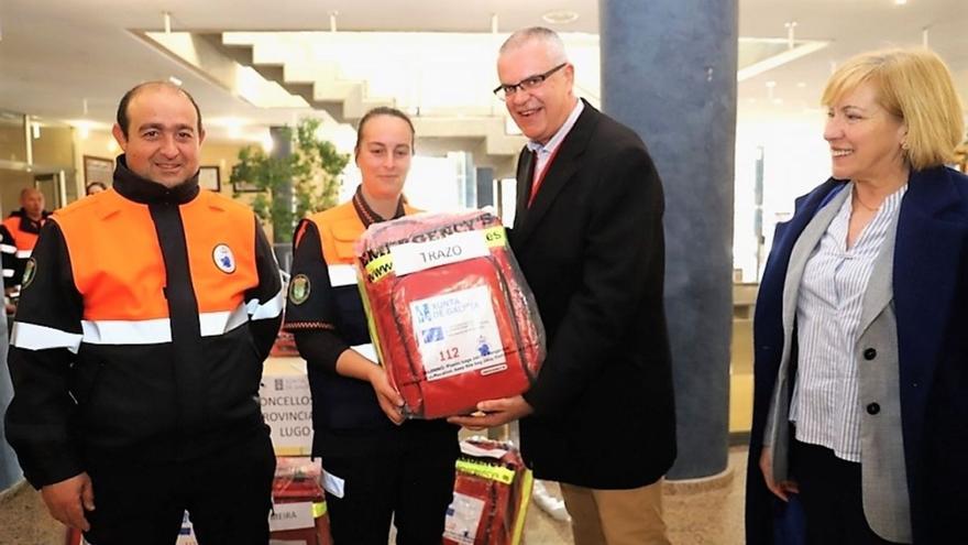 Miembros de la AVPC de Trazo, Óscar Noya, izqda. y Noelia Martínez, reciben un desfibrilador del director de Emerxencias ante su regidora