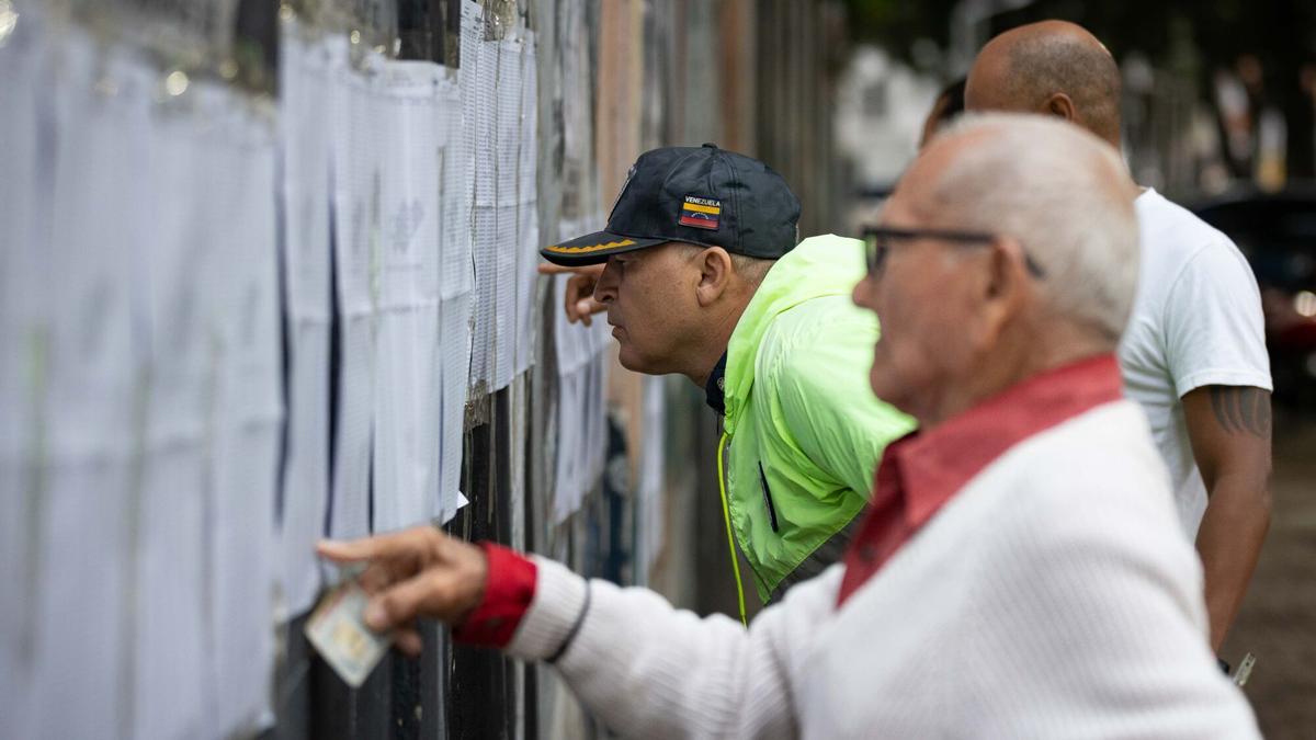 Personas observan las listas de las mesas de votación.