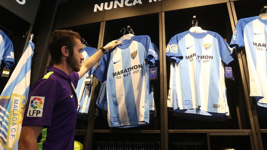 Imagen de un seguidor blanquiazul en la tienda oficial de La Rosaleda comprando una camiseta del Málaga CF.