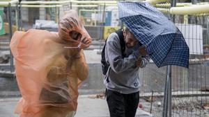 Unos turistas cruzan la Diagonal de Barcelona bajo la lluvia.