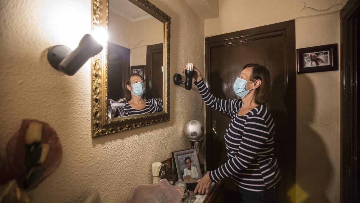 Una mujer toca una bombilla apagada en su casa, en una imagen de archivo.