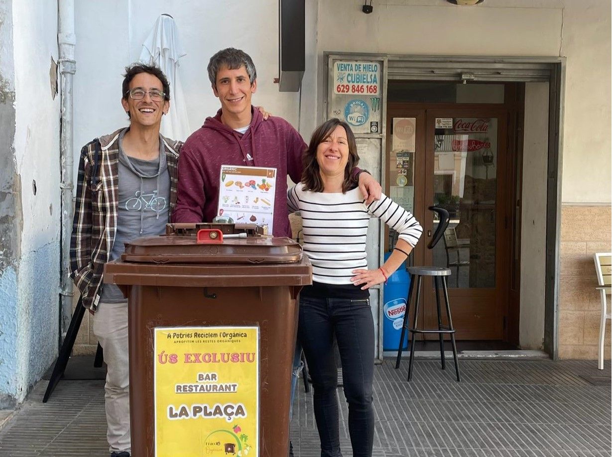 El concejal de Medio Ambiente y la educadora ambiental con el propietario del Bar La Plaça.