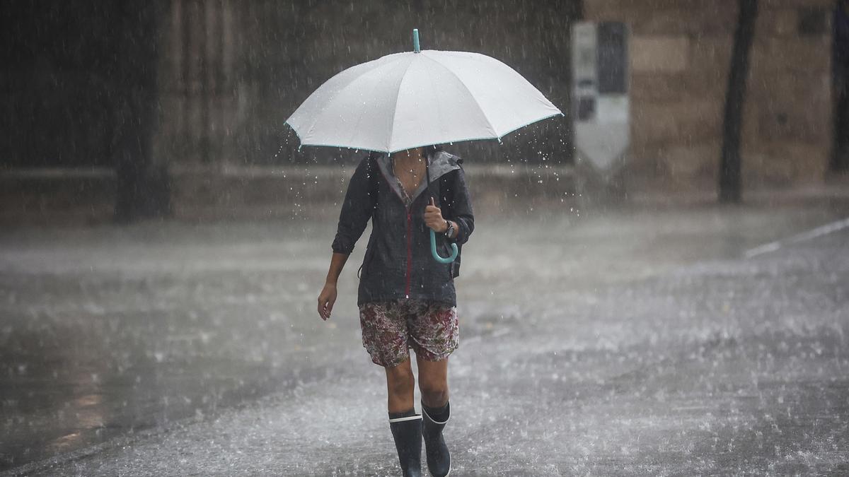 Una mujer camina bajo una intensa lluvia durante la tormenta de este miércoles.  SOBRE VALENCIA