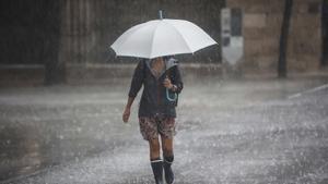 Una mujer camina bajo una intensa lluvia durante la tormenta de este miércoles.