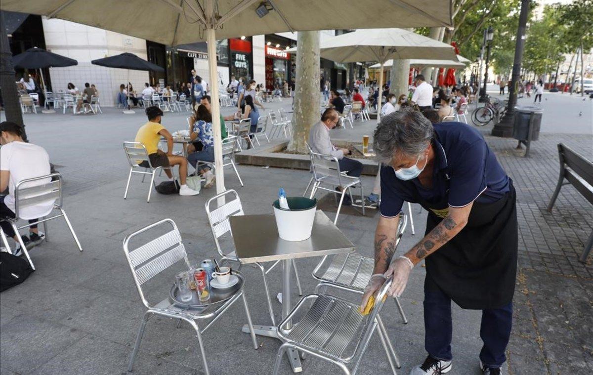 Un camarero limpia una silla en el Café Zurich, en la plaza de Catalunya.