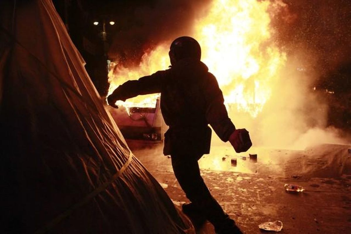 Un manifestant pro-europeu llança una pedra durant els enfrontaments amb la policia antiavalots.