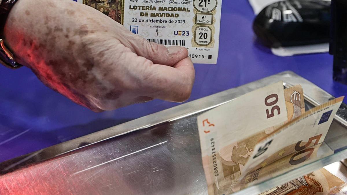 Una persona compra un décimo de Lotería de Navidad en una administración de Barcelona. / ANA PUIT