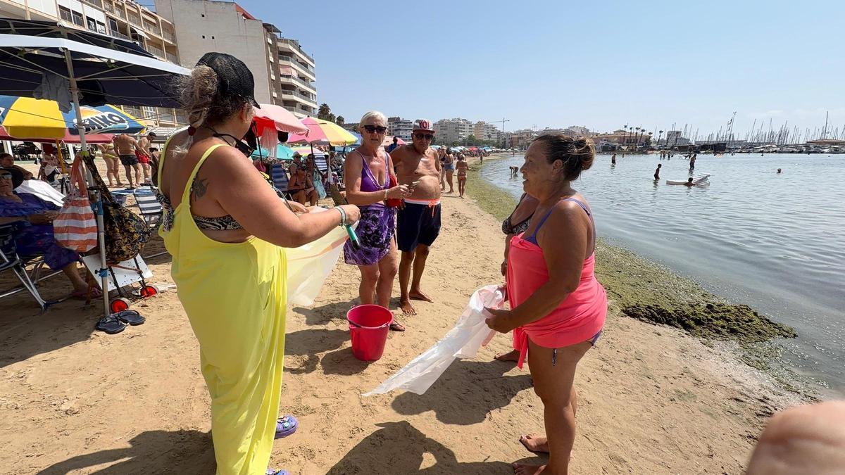 Bañistas pertrechados con bolsas protestan contra la falta de limpieza de la marea verde