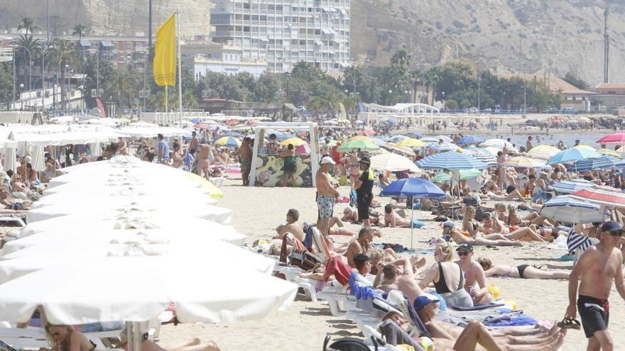 La playa del Postiguet con bandera amarilla. En el centro, un policía charla con bañistas