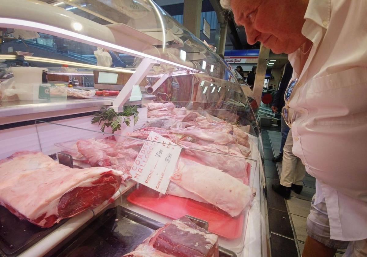 Un hombre mirando los precios del cordero.