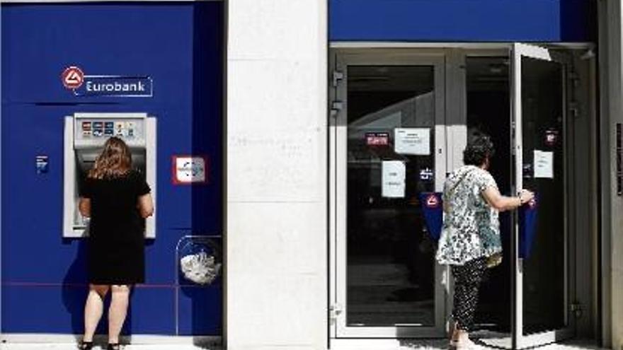 Una dona treu diners del caixer d&#039;un banc a Atenes.