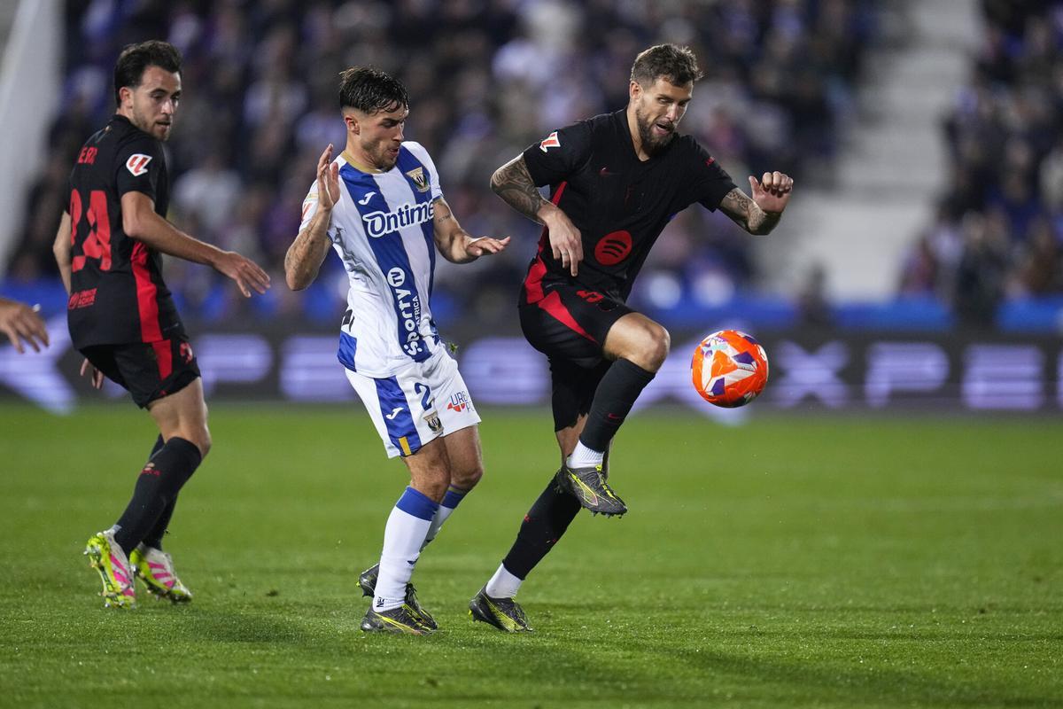 Barcelona's Inigo Martinez, right, and Leganes' Adria Altimira challenge for the ball during the Spanish La Liga soccer match between CD Leganes and Barcelona at the Butarque stadium in Leganes, outside Madrid, Spain, Saturday, April 12, 2025. (AP Photo/Manu Fernandez)