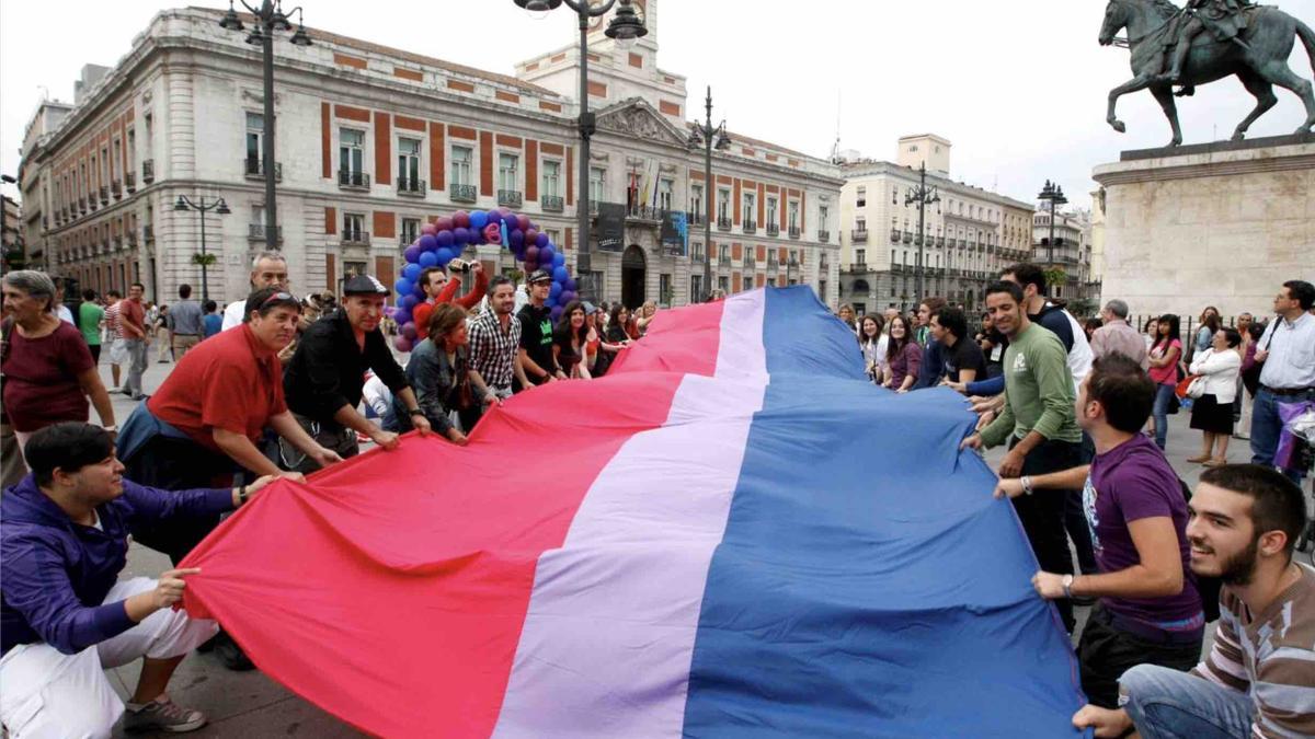 Representantes de la Felgtb despliegan una bandera bisexual.