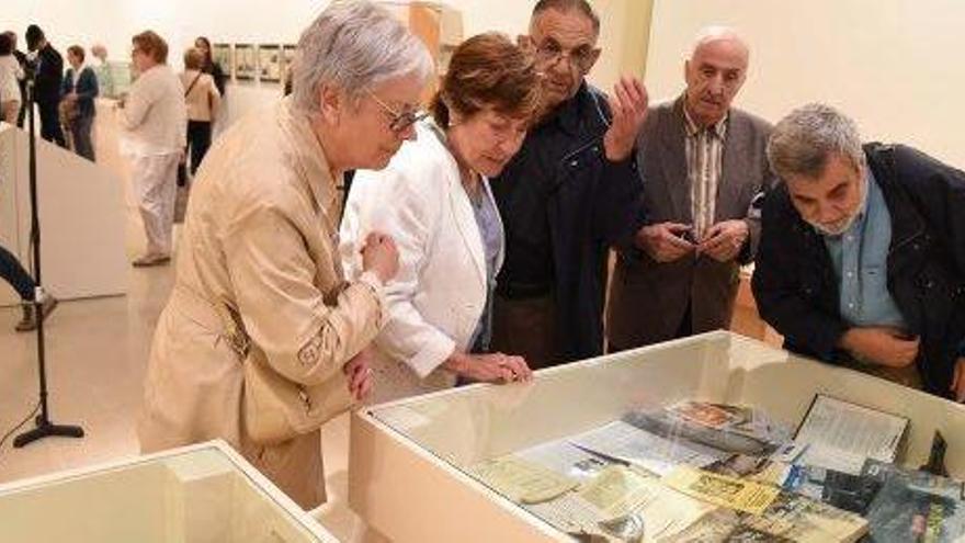 Diverses persones observen una de les vitrines de la mostra, amb llibres i publicacions