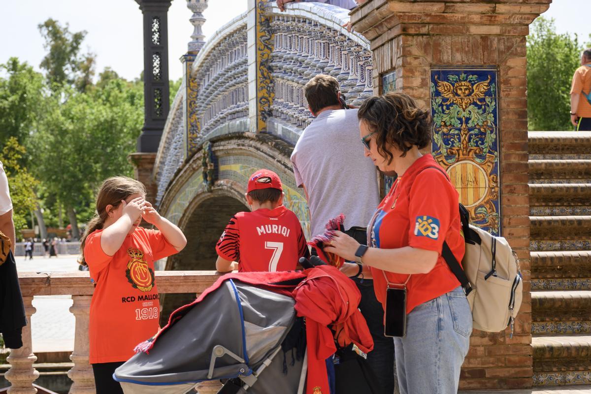 Una familia de aficionados del Real Club Deportivo Mallorca pasean por la Plaza de España de Sevilla.