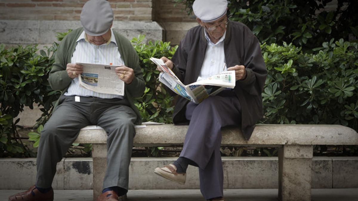 Dos jubilados leen la prensa en un parque del centro de Valencia