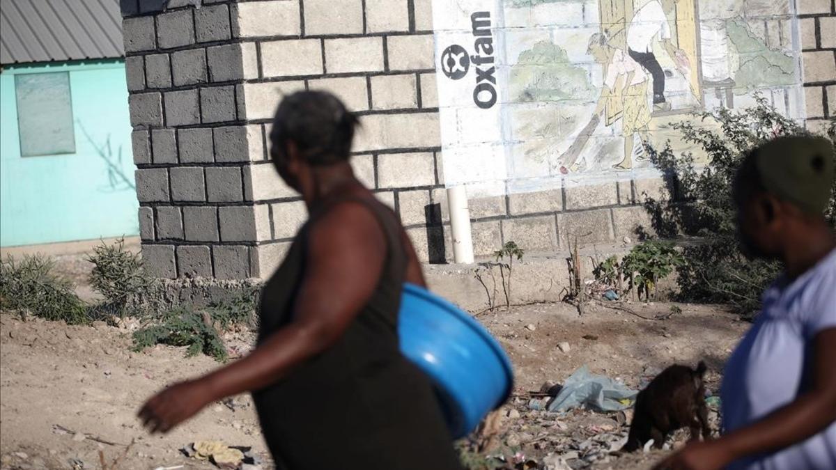 Dos mujeres pasan ante un mural de Oxfam en Puerto Príncipe, Haití.