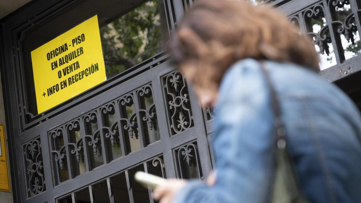 Una mujer pasa ante un cartel anunciando el alquiler de una vivienda en el Eixample de Barcelona.