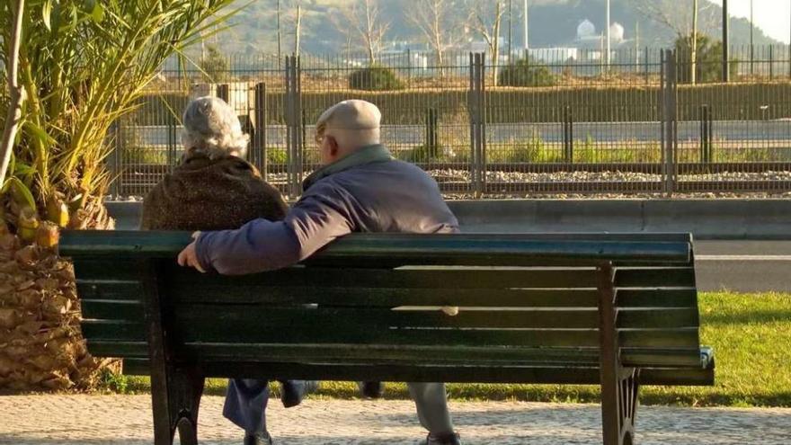Una pareja de mayores sentados en un banco.