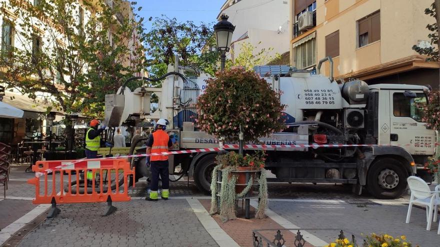 Dos operarios limpian un imbornal en Estepona.